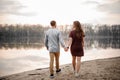 Couple in love walking on a wet sand along the lakeside on the background of trees