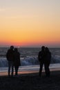 Couple in love watching sunset together on beach travel summer holidays. People silhouette from behind sitting enjoying Royalty Free Stock Photo