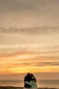 Couple in love watching sunset together on beach travel summer holidays. People silhouette from behind sitting enjoying Royalty Free Stock Photo