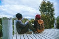 Couple lover natural travel on the mountain, sitting relax reading books in the midst of nature on the white wooden bridge