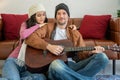 Romantic couple sitting on floor in living room. Man playing guitar and singing with woman , enjoying great time together at home Royalty Free Stock Photo