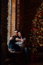 Couple of lovers hugs sitting on the windowsill in the Christmas loft studio. guy is hugging the girl.