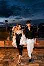 Couple of lovers on the roof in the evening at sunset, walking on the luxurious penthouse balcony, enjoying beautiful