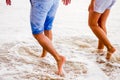 Couple of lovers walking on the sea foam on the beach at sunset. Feet close up. Royalty Free Stock Photo