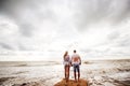 Couple of lovers walking on the sea foam on the beach at sunset. Looking at the ocean. Royalty Free Stock Photo