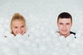 Couple of loving friends have fun surrounded by white plastic balls in a dry swimming pool. Royalty Free Stock Photo