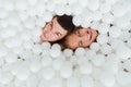 Couple of loving friends have fun surrounded by white plastic balls in a dry swimming pool. Royalty Free Stock Photo