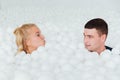 Couple of loving friends have fun surrounded by white plastic balls in a dry swimming pool. Royalty Free Stock Photo