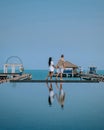 Couple on luxury vacation in Thailand, men and woman infinity pool looking out over the ocean