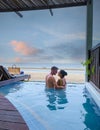 Couple in luxury villa enjoying in the plunge pool looking out over ocean and beach during sunset