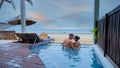 Couple in luxury villa enjoying in the plunge pool looking out over ocean and beach during sunset