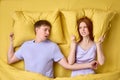 Couple lying in bed, redhead woman is trying to sleep while man is snoring Royalty Free Stock Photo
