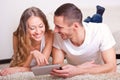 Couple lying on carpet and looking at tablet Royalty Free Stock Photo