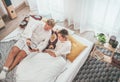 Couple lying in a cozy bed in the bedroom and browsing together the internet or checking mails using a modern smartphone. Modern Royalty Free Stock Photo