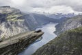 Couple lying down on trolltunga troll`s tongue rock , Norway