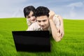 Couple lying on grass looking at laptop Royalty Free Stock Photo