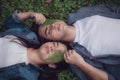 Couple lying in the woods next to each other with a leaf on their face