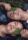 Couple lying in the woods next to each other with a leaf on their face