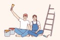 Couple makes repairs in apartment with own hands and sits on floor near ladder and buckets of paint Royalty Free Stock Photo