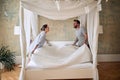 Couple making bed.Charming man and woman in love making bed together