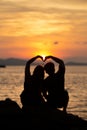 Couple making heart shape on the beach in sunset. Royalty Free Stock Photo