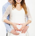 Couple making a heart shape on the pregnant belly with their hands. Concept of pregnancy, expecting a baby, love, care,cropped Royalty Free Stock Photo