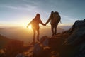 Couple of man and woman hikers on top of a mountain at sunset or sunrise