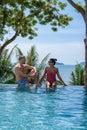 couple man and woman mid age in swimming pool on a luxury vacation in Thailand, men and Asian woman in pool looking out Royalty Free Stock Photo