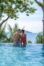 couple man and woman mid age in swimming pool on a luxury vacation in Thailand, men and Asian woman in pool looking out Royalty Free Stock Photo