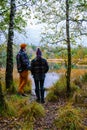 couple man and woman mid age walking in the forest during Autumn season in nature trekking with orange red color trees Royalty Free Stock Photo