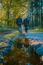 couple man and woman mid age walking in the forest during Autumn season in nature trekking with orange red color trees Royalty Free Stock Photo