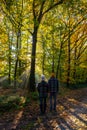 couple man and woman mid age walking in the forest during Autumn season in nature trekking with orange red color trees Royalty Free Stock Photo