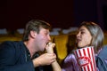 Couple man and woman are seating and eating popcorn at cinema movie theater seats. The faces have feeling happy and enjoy Royalty Free Stock Photo