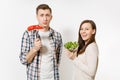 Couple, man, woman standing with green fresh salad in glass bowl, red hot chili pepper on fork isolated on white Royalty Free Stock Photo