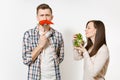 Couple, man, woman standing with green fresh salad in glass bowl, red hot chili pepper on fork isolated on white Royalty Free Stock Photo