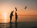 Couple of man and woman standing in the sea and throw your shoes at the beach.