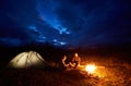 Couple man and woman tourists having a rest at night camping in the mountains under cloudy sky Royalty Free Stock Photo