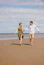 a couple of a man and a woman are walking on the beach or running along the sand along the seashore. beautiful and young Royalty Free Stock Photo