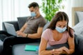 Couple man and woman work and sit on sofa in living room and they stay far from each other to concept of social distancing during Royalty Free Stock Photo