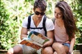 Couple, map and backpack for hiking in forest with reading for thinking, holiday or search by trees. Man, woman and bag Royalty Free Stock Photo