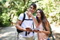 Couple, map and point for hiking in forest with reading for thinking, holiday and ideas on path. Man, woman and bag for Royalty Free Stock Photo