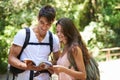 Couple, map and reading for hiking in woods with smile for thinking, holiday and ideas on path. Man, woman and bag for Royalty Free Stock Photo