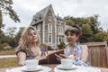 Couple of mature friendly women on vacation drinking tea and reading a book outdoors Royalty Free Stock Photo