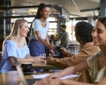 Couple Meeting In Busy Coffee Shop Being Served At Table By Waitress