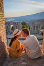 Couple men and woman visit Ruins of Ancient Greek theatre in Taormina on background of Etna Volcano, Italy. Taormina Royalty Free Stock Photo