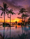 couple men and woman watching sunset on a tropical beach in Mauritius with palm trees by the swimming pool, Tropical Royalty Free Stock Photo