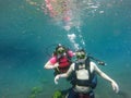 Couple of man and woman dive underwater with the oxygen tank equipment, vest, snorkel, fins, regulator enjoy the sport activity Royalty Free Stock Photo