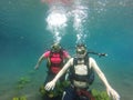 Couple of man and woman dive underwater with the oxygen tank equipment, vest, snorkel, fins, regulator enjoy the sport activity Royalty Free Stock Photo