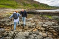 A couple of men and women walking on large eroded rocks on the Isle of Skye, Scotland.