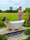 men and women in bath tub outside on vacation at a homestay in Thailand with green rice paddy field Royalty Free Stock Photo